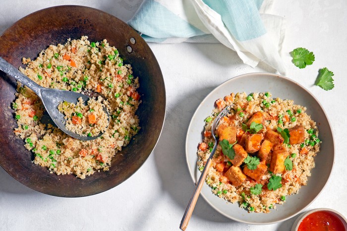 Cauliflower rice and baked tofu A cauliflower rice dish with a red sauce on the side
